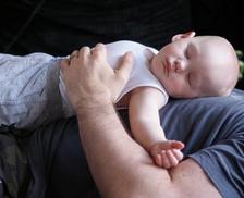 Secure baby asleep on father's chest